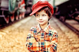 Foto de um menino com camisa xadrez e boné vermelho para demonstrar visão amarelada