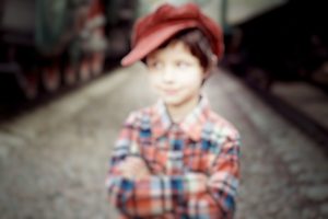 Foto de um menino com camisa xadrez e boné vermelho para demonstrar visão embaçada