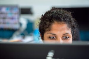 Uma mulher em um escritório, olhando para a tela do computador