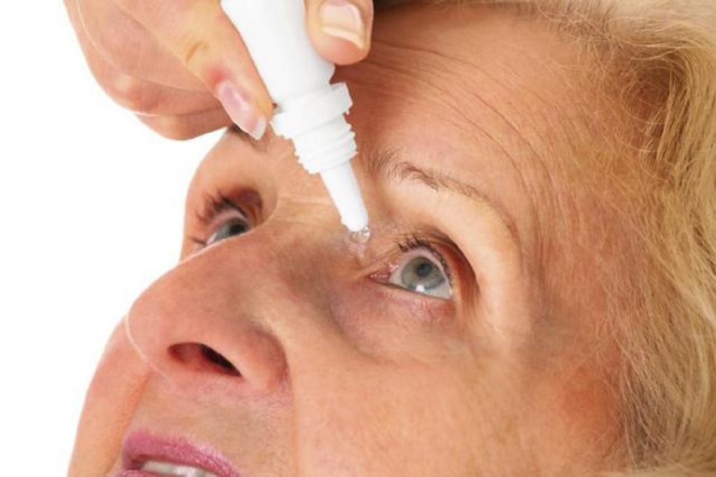 Uma senhora aplicando colírio nos olhos