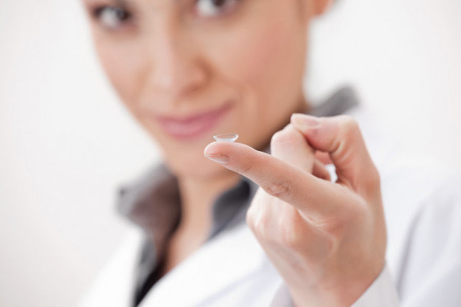 Oftalmologista com uma lente de contato rígida na ponta de seu dedo indicador.