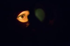 imagem de um olho iluminado com todo o resto escuro, simulando um exame para detecção de hordéolo interno