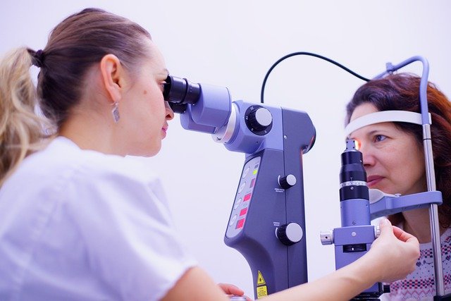 Mulher realizando exame oftalmológico em outra mulher com auxílio de equipamento