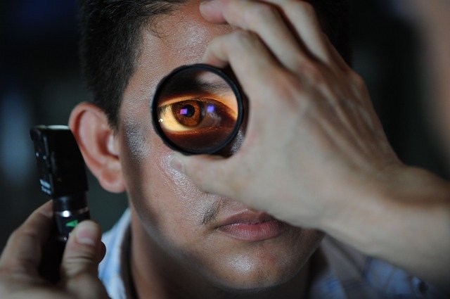 Pessoa tendo o olho examinado com uma lupa de aumento