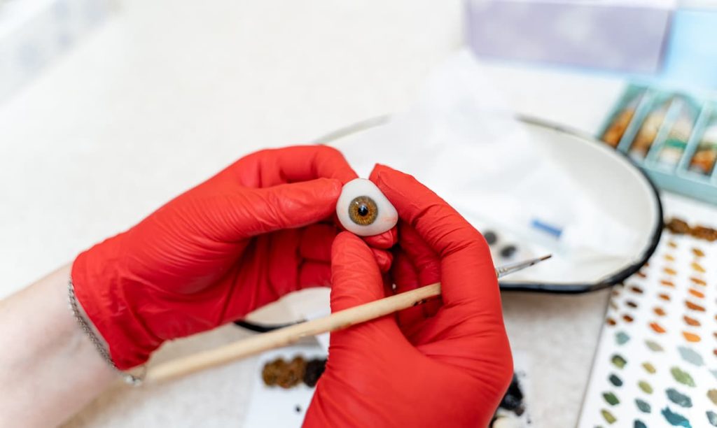 Uma pessoa faz o processo de acabamento artesanal de uma prótese ocular.