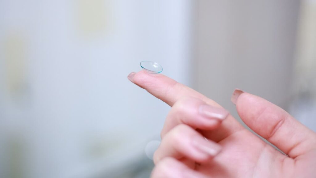 Imagem de uma pessoa segurando uma lente de contato em seu dedo