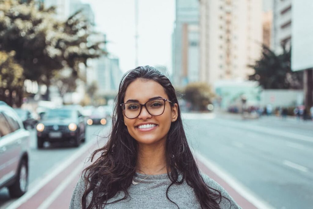 Imagem de uma mulher sorrindo de óculos em uma avenida