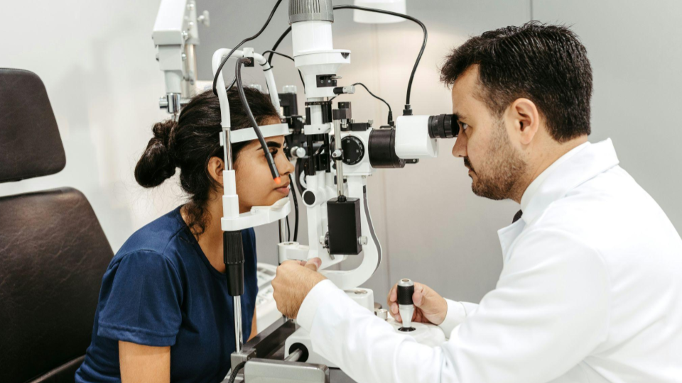 Um médico oftalmologista realiza um exame detalhado em uma paciente utilizando uma lâmpada de fenda (biomicroscópio).