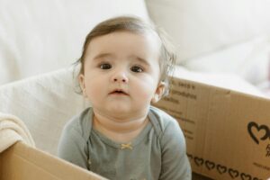 Bebê com estrabismo em uma caixa de papelão.
