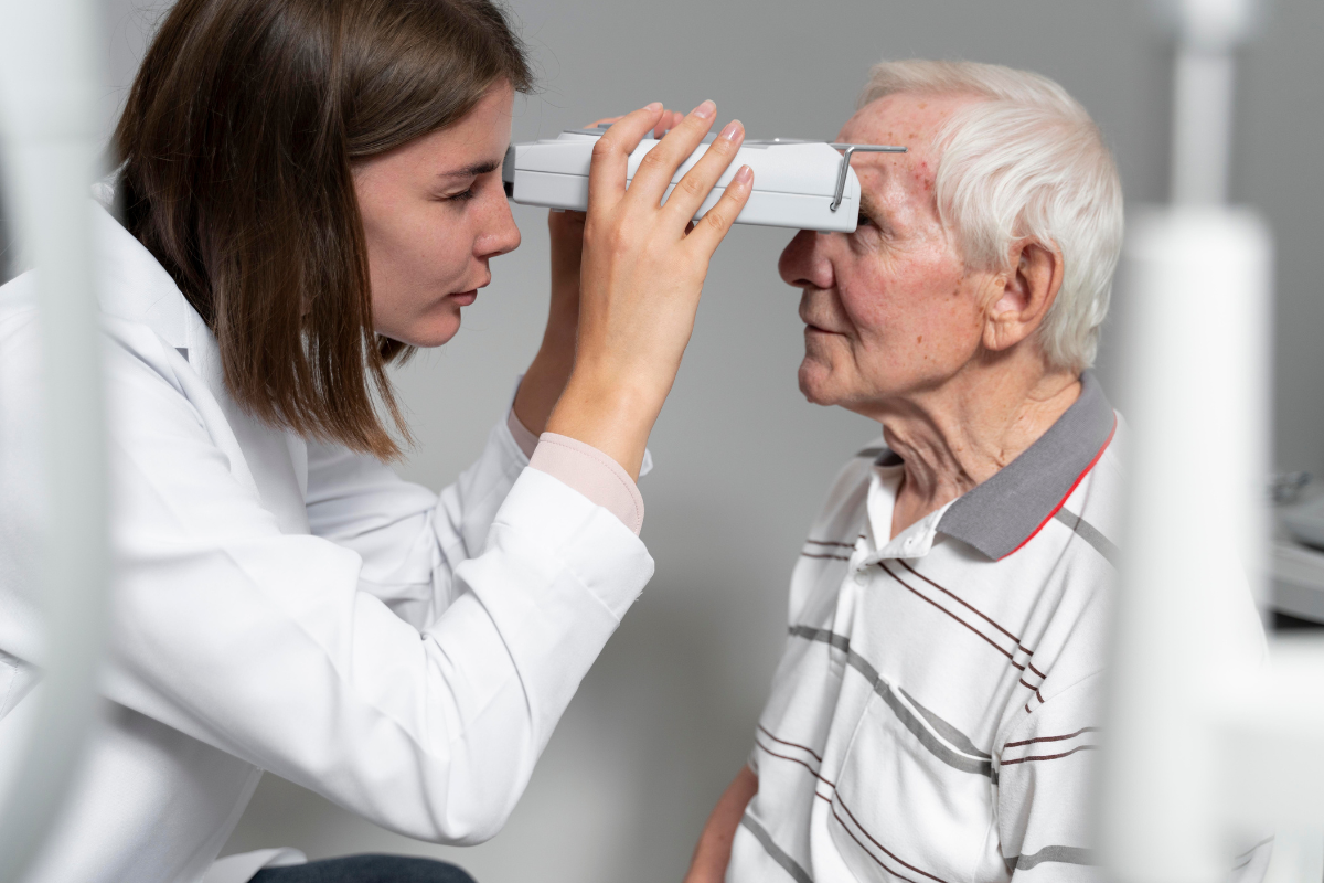 A imagem mostra uma profissional de saúde — possivelmente uma oftalmologista ou optometrista — realizando um exame ocular em um senhor idoso.