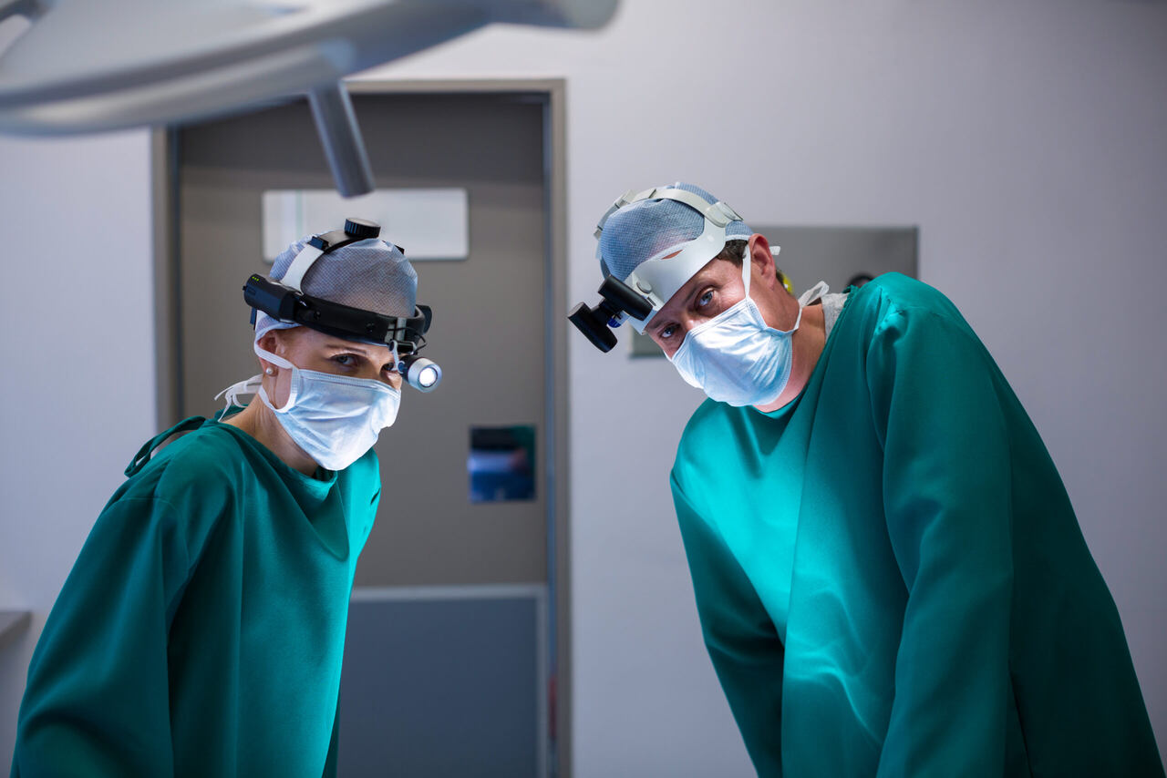 médicos de uniforme verde ouvindo perguntas para fazer ao oftalmologista antes da cirurgia de catarata