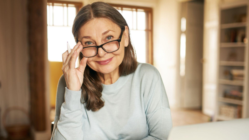 Esta imagem apresenta uma mulher de meia-idade com uma expressão serena e intelectual.