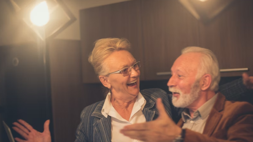 Esta imagem apresenta um casal de idosos em um momento de celebração ou alegria compartilhada.