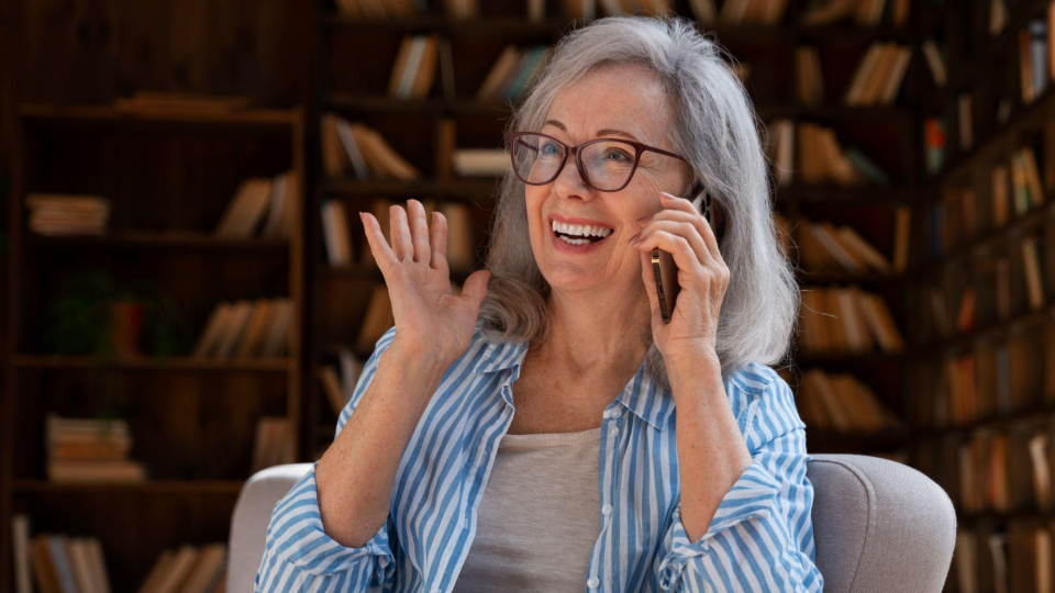 Imagem retrata uma mulher usando óculos e sorrindo ao celular