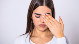 A imagem mostra uma mulher jovem expressando desconforto ocular e vista cansada.