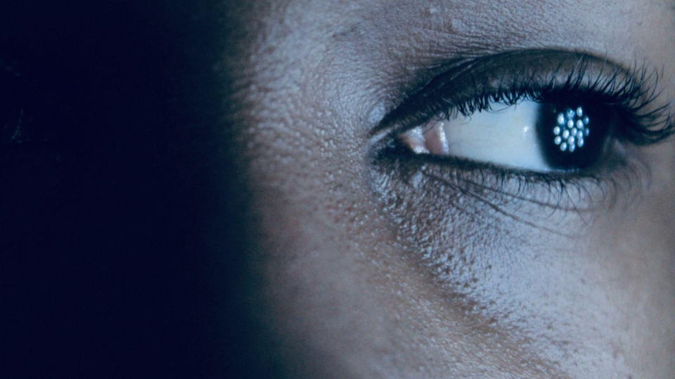 A imagem apresenta um close extremo de um olho humano, com foco nos detalhes da pele e da íris.