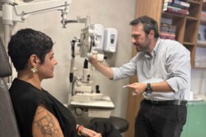 Médico conversa com paciente em clínica de oftalmologia durante consulta.